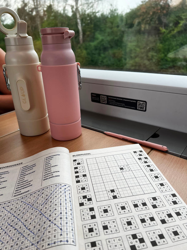 Twee Gloup Grips in Dune creme en Dusty blush op een treintafeltje bij een puzzelboek